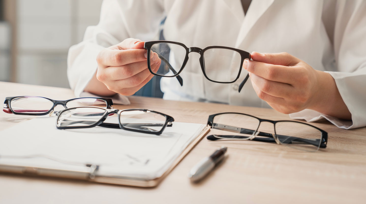 Gros plan sur les mains d'un opticien effectuant des ajustements précis sur une monture de lunettes avec des outils spécialisés